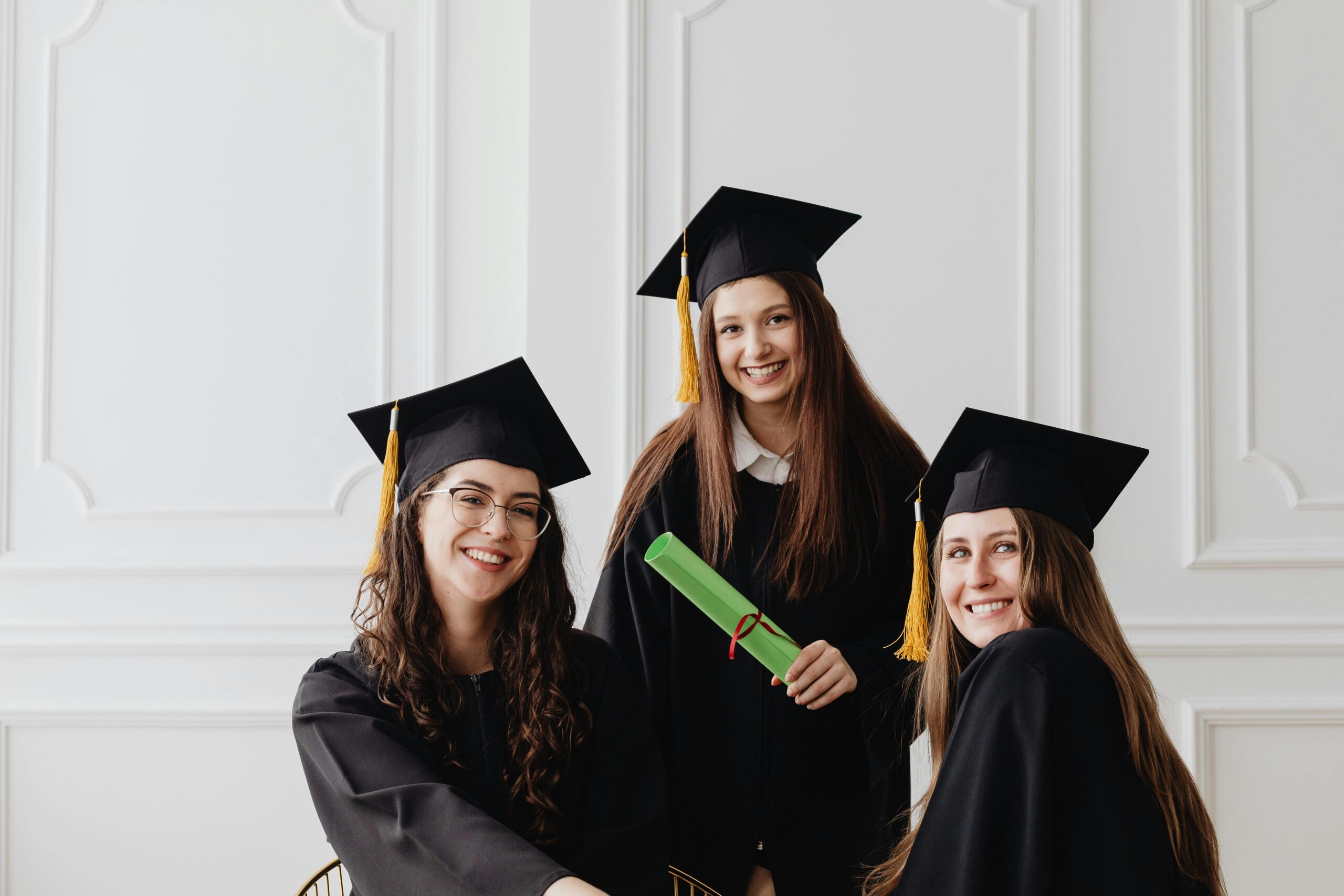 A group of recent graduates smiling while holding their diplomas